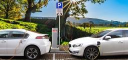 two parked electric vehicles plugged into charging stations
